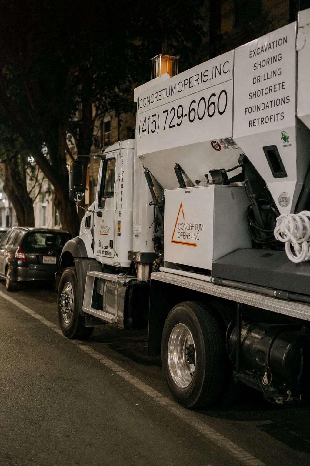 Concretum Operis mixer truck on a city street at night